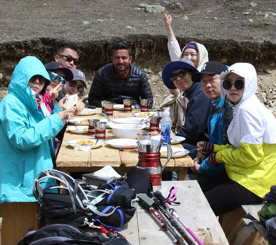 Musa Karim with a group of travellers at a meal in the mountains